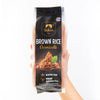 Hand holding a package of Siam Brown Rice Vermicelli on a white background