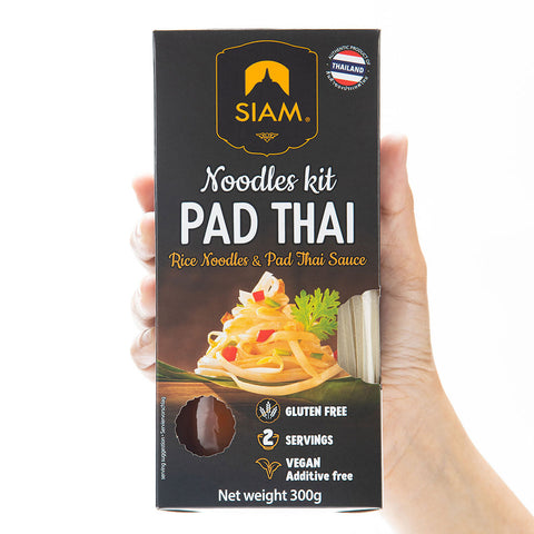 Siam Pad Thai noodles kit packaging held by a hand on a white background
