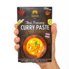 Hand holding a package of SIAM Thai Panang Curry Paste on a white background
