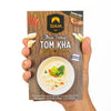 Hand holding a package of Siam Thai Soup Tom Kha with wooden design