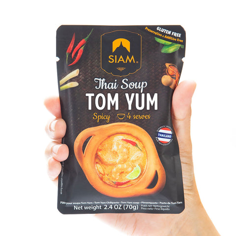 Hand holding a Siam Thai Soup Tom Yum package against a white background